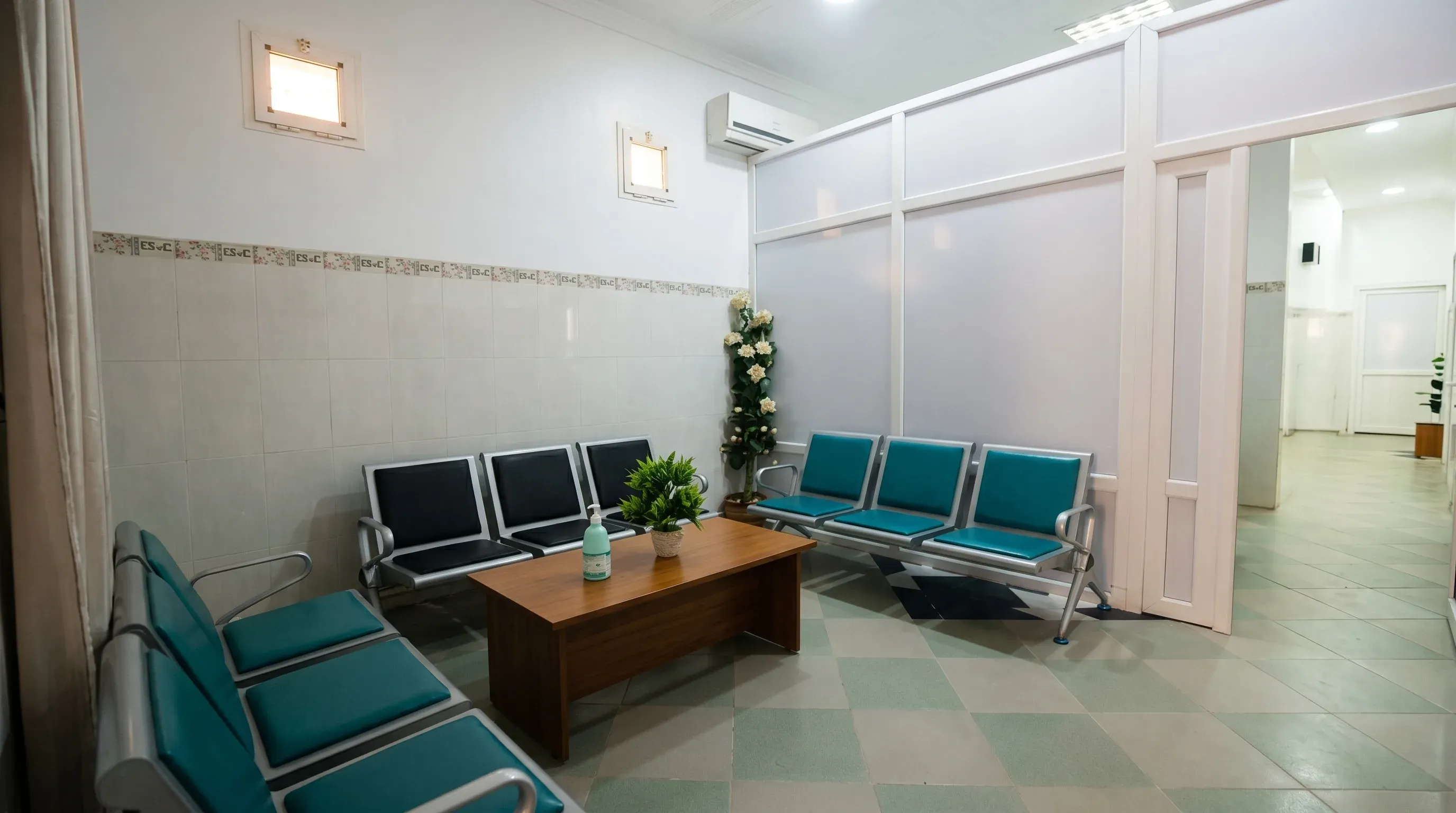 Salle d'attente du service : rangées de sièges, table basse et plantes